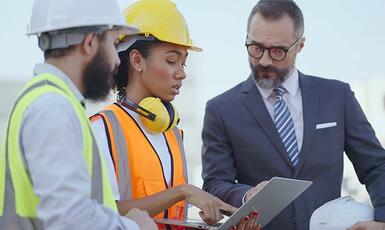 Industrial workers look at a laptop and ensure safety measures